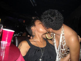 Dark-hued girl-on-girl femmes kissing on the party