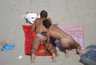 Some middle-aged couples sunbathing on naturist beach.
